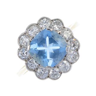 An aquamarine and diamond cluster ring. The cushion-shape aquamarine, within a brilliant-cut diamond