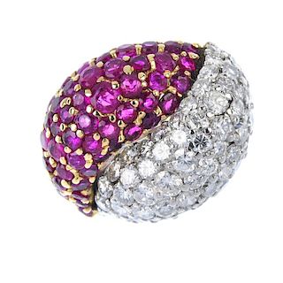 A diamond and ruby dress ring. Of bi-colour design, the two crossover domed panels, pave-set with ci