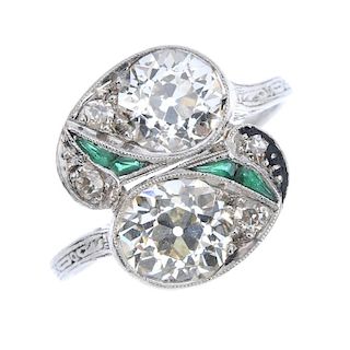 An Art Deco platinum diamond and emerald crossover ring. Of asymmetric design, the two old-cut diamo