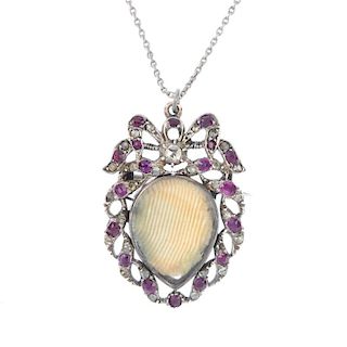 A ruby and diamond photograph pendant. Designed as a vacant pear-shape glazed panel, within a vari-s