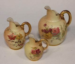 A Royal Worcester blush ivory cleft jug, puce mark of eight dots, 17.5cm high, and two smaller jugs