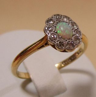 An opal and diamond cluster ring, the central oval opal cabochon surrounded by small round diamonds