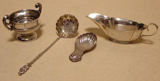 A silver shell shaped caddy spoon, a sauce boat, a small twin handled cup and a silver sugar sifter