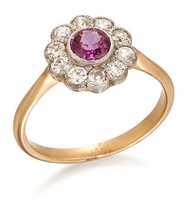 A RUBY AND DIAMOND CLUSTER RING, a round-cut ruby within a border of milgra