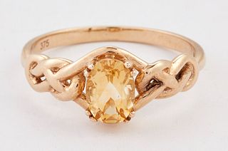 A 9 CARAT GOLD CITRINE RING, an oval-cut citrine between Celtic-knot should