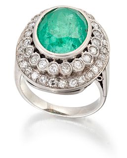 AN EMERALD AND DIAMOND CLUSTER RING, an oval-cut emerald in a bezel setting