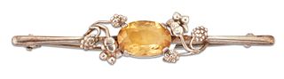 AN ARTS AND CRAFTS CITRINE BROOCH, an oval-cut citrine spaced by sprays of 
