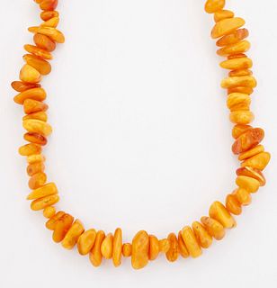 AN AMBER BEAD NECKLACE, of roughly polished beads as a continuous strand. 1