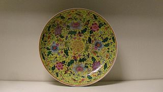 A yellow ground dish, painted with flowers scrolling around the central gilt shou character within t