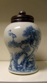 An 18th century blue and white baluster jar with wood cover, the sides painted with a continuous sce