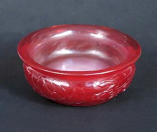 A Peking red glass butter tea bowl, the rounded sides below the flared rim carved with two dragons f