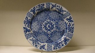 An 18th century blue and white dish painted with brocade and flower panels radiating around a centra