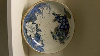 A 19th century shallow bowl painted in blue and gilt with a shishi above waves and a peony, spots of