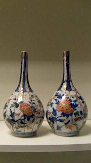 A pair of early 18th century Imari bottle vases, the slender necks with blue panels alternating with