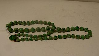 A carved jadeite bead necklace, the emerald green beads diminishing in size to the gold mounted rose