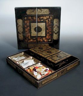 A mid 19th century black lacquer games box, gilt floral panels and grape vine bands enclosing the ce
