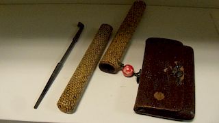 A pipe and tobacco pouch sagemono, the bamboo stemmed pipe with bowl and mouthpiece iroe on a shakud