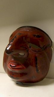 A lacquer mask, possibly of Shin Sotoku, a red tongue protuding from the brown face with black hair,