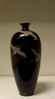 An early 20th century cloisonne vase, cranes flying down the slender ovoid body from the shoulders a