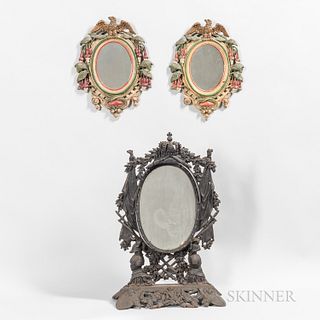 Three Cast Iron Mirrors, a 19th century standing oval mirror with elaborate frame with crown crest flanked by flags and supported atop