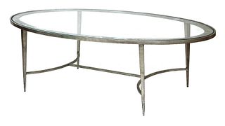 An oval glass-topped aluminium coffee table,