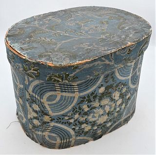 Hannah Davis Large Wallpaper Covered Hat Band Box
bentwood covered with blue wallpaper having scrolling vines and flowers with newspaper lining 
paper