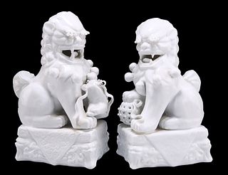 A NEAR PAIR OF CHINESE BLANC DE CHINE MODELS OF BUDDHIST LIONS, wearing bel