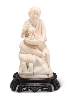 A 19TH CENTURY JAPANESE CARVED IVORY OKIMONO, modelled as a man resting upo