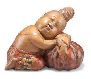 A BALINESE CARVING OF A BOY, resting on a gourd. 23.5cm long