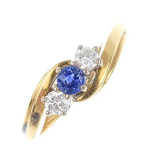 An 18ct gold sapphire and diamond crossover ring. The circular-shape sapphire, with brilliant-cut di