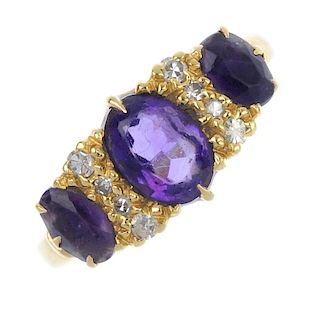 An 18ct gold amethyst three-stone and diamond dress ring. The graduated oval-shape amethyst line, wi