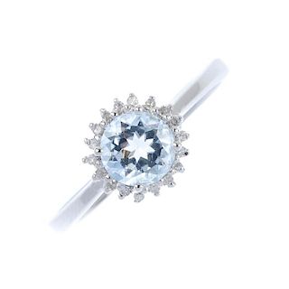 A 9ct gold aquamarine and diamond cluster ring. The circular-shape aquamarine, within a single-cut d