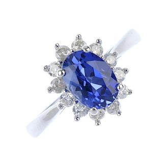 A 9ct gold sapphire and diamond cluster ring. The oval-shape sapphire, within a brilliant-cut diamon