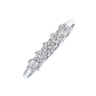 An 18ct gold diamond five-stone ring. The brilliant-cut diamond line, to the tapered shoulders and p