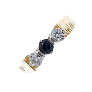 An 18ct gold sapphire and diamond three-stone ring. The circular-shape sapphire and brilliant-cut di