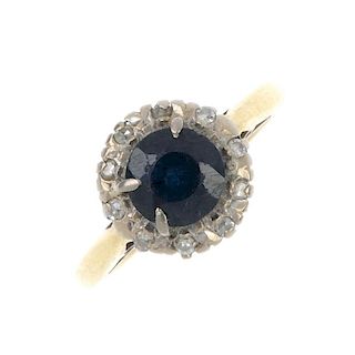 An 18ct gold sapphire and diamond cluster ring. The circular-shape sapphire, within a single-cut dia