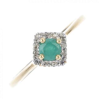 A 9ct gold emerald and diamond cluster ring. The circular-shape emerald, within a single-cut diamond