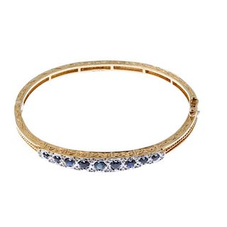 A 9ct gold sapphire and diamond hinged bangle. Designed as a series of graduated circular-shape sapp
