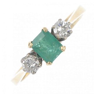An 18ct gold emerald and diamond three-stone ring. The rectangular-shape emerald, with brilliant-cut