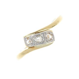 A mid 20th century 18ct gold diamond three-stone ring. The rose-cut diamond line, to the asymmetric