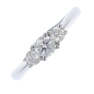 An 18ct gold diamond three-stone ring. The brilliant-cut diamond, with similarly-cut diamond sides,