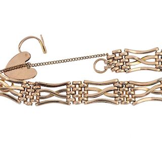 An early 20th century 9ct gold gate bracelet. Designed as a series of crossover bar gate-links, to p