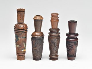 Four heavily carved duck calls by different makers.