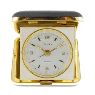An alarm travel clock by Deluxe. Gold plated case. Quartz movement. Silvered dial with baton hour ma