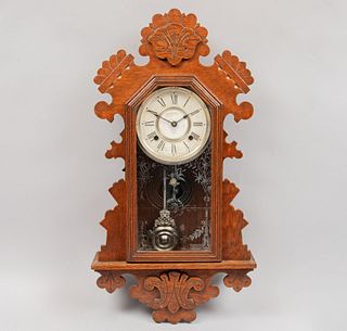Reloj de pared. SXX. Elaborado en madera. Mecanismo de péndulo, índices romanos y manecillas tipo pera. 64 x 34 x 10 cm.