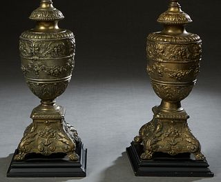Pair of Brass Baluster Urns, late 19th c., with relief fruit and floral decoration. to a sloping floral relief square base on paw feet, now mounted on