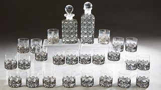 Unusual Twenty-Six Piece Crystal Liqueur Set, 20th c., in silvered metal holders, consisting of twenty-four small glasses and two matching decanters, 