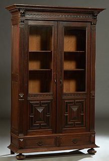 French Henri II Style Carved Oak Bookcase, c. 1880, the stepped lion carved crown over double setback doors with glazed upper panels over lower geomet