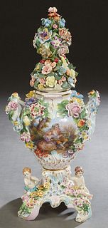 Dresden Style Covered Porcelain Urn, 20th c., with a relief floral lid over a baluster body with relief floral decoration and two putti on the base, m
