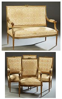 French Louis XVI Style Carved Beech Giltwood Parlor Suite, late 19th c., consisting of a settee and four fauteuils, all with floral twist carved crest